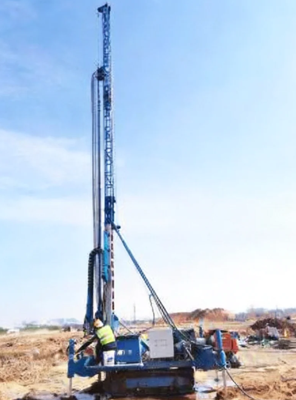Workers operating AM-6 rotary drill at backfilled soil layer site